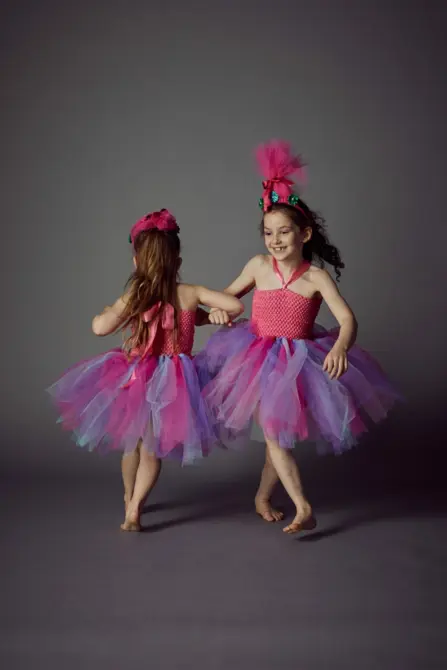 two young girls arm in arm dancing in tutu