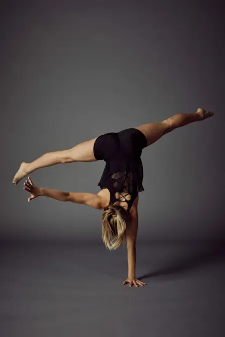 young girl doing a wide leg one handed hand stand