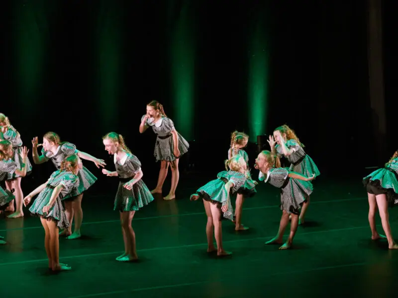 young girls on stage performing making faces at each other