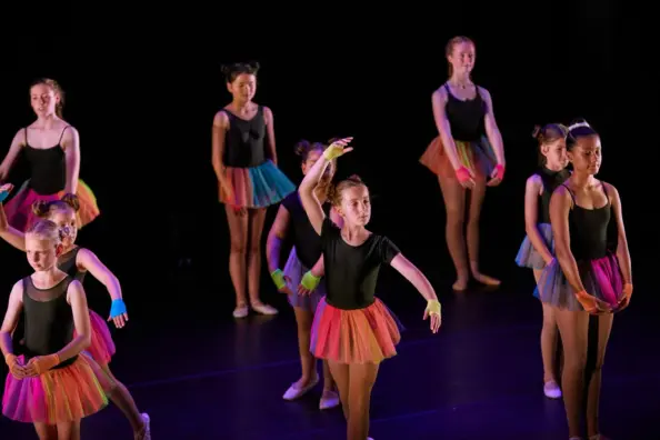 girls performing ballet on stage in rainbow tutu