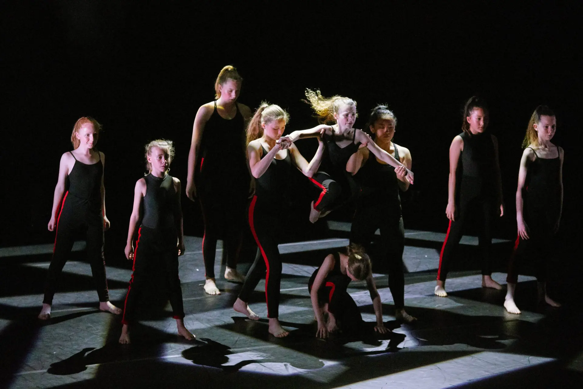 girl leaping over other girl in a performance on stage