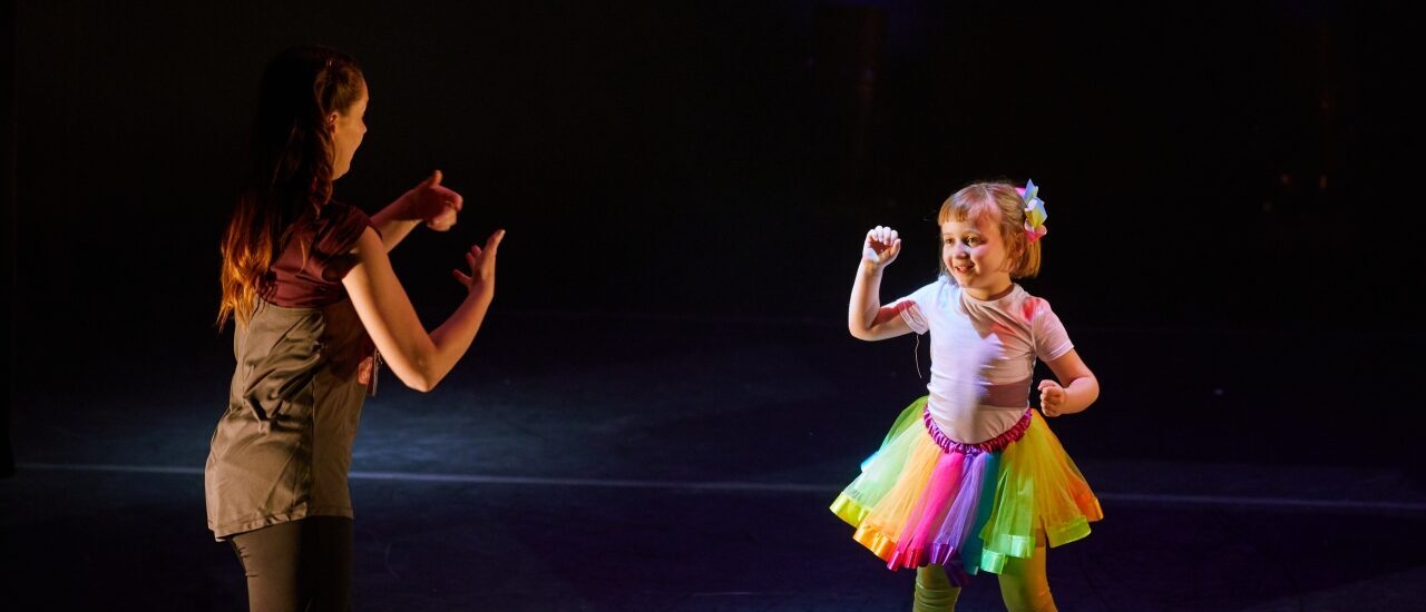 young girl in tutu with teacher on stage
